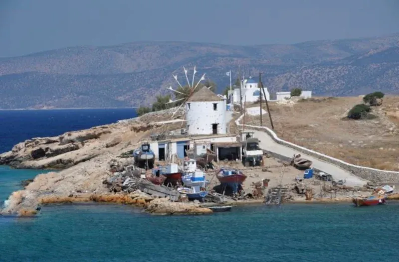 Windmill and fishing boats on a rocky point beside a small island harbour
