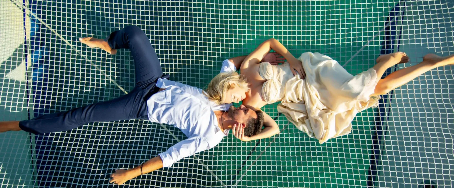 Bride and groom lying on the net of a catamaran, seen from above