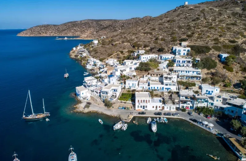 White village and small harbour on a dry hillside on Amorgos, a yacht at anchor