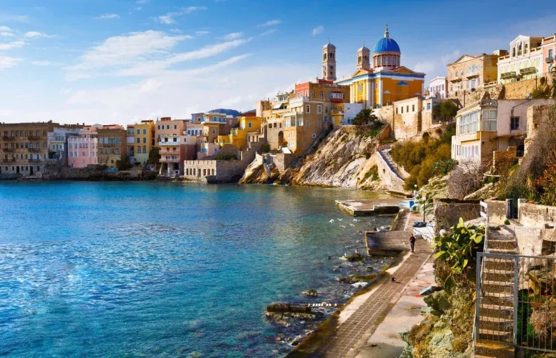 Pastel houses and a blue-domed church above the seafront promenade of Ermoupoli