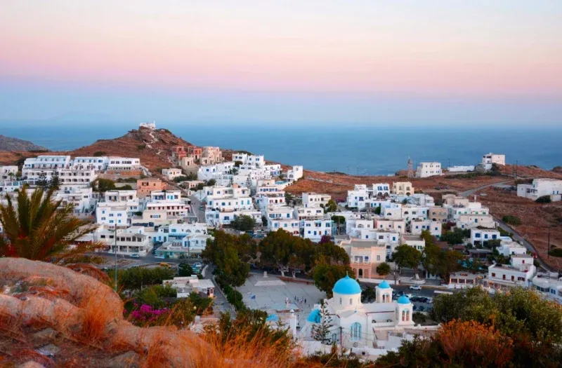 White houses of Ios town and a blue-domed church in the evening light