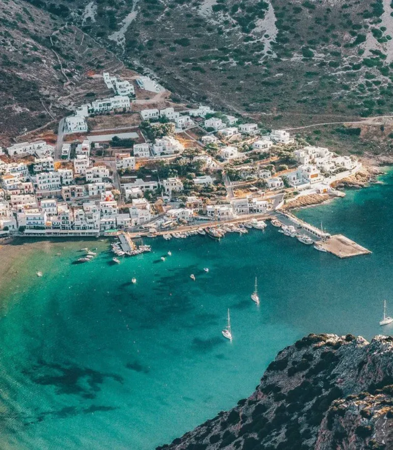 Harbour village and turquoise bay with yachts at anchor on Sifnos, seen from above
