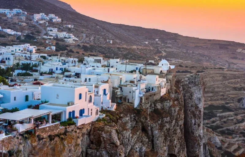 White houses of Folegandros town on the edge of a cliff at sunset