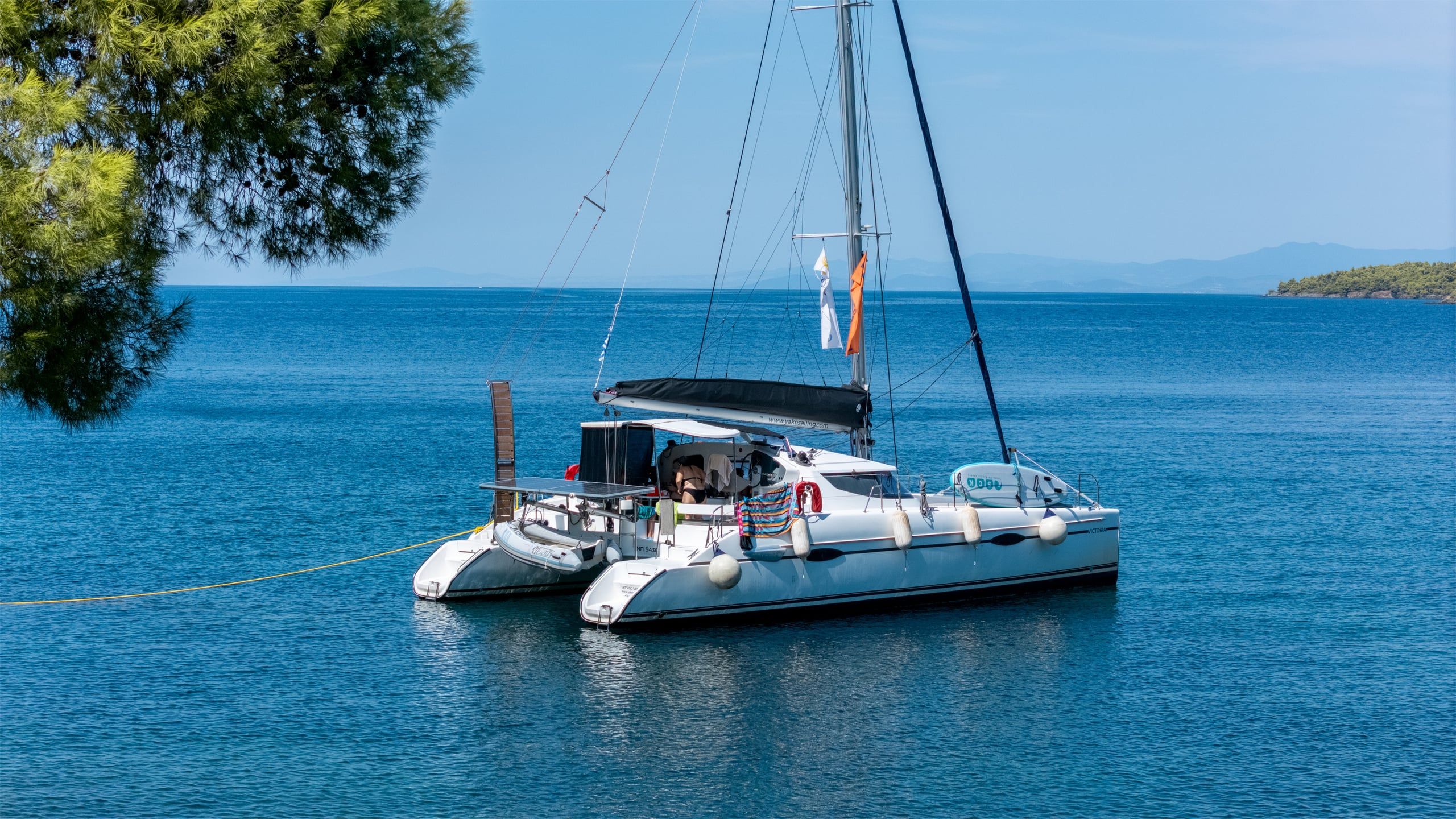 Catamaran moored off a pine shore in calm blue water at Agia Kyriaki