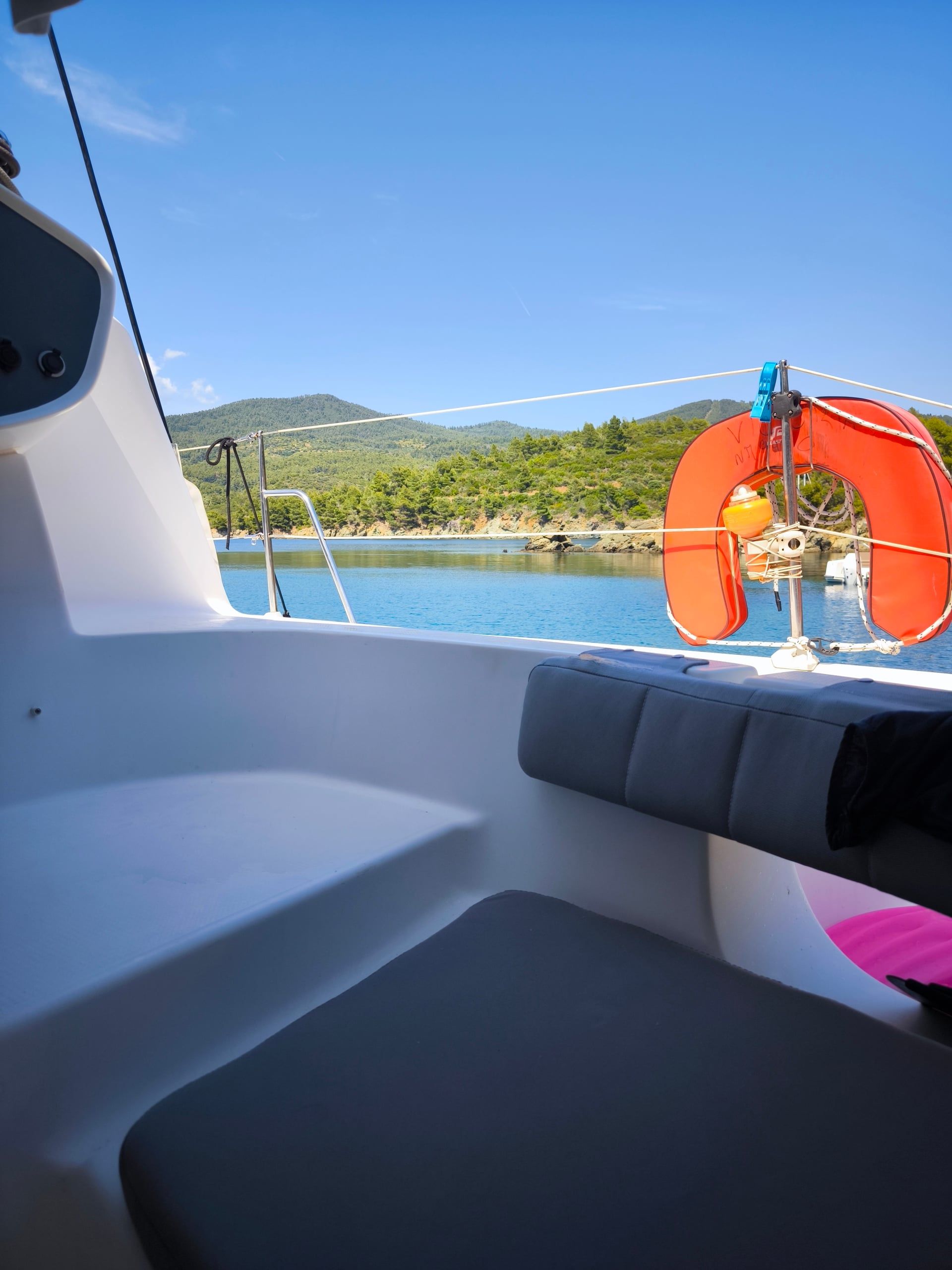 View from a catamaran cockpit to a wooded bay and clear water