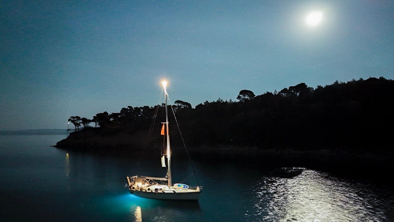 Sailing yacht lit at night under a full moon in a bay on Alonnisos