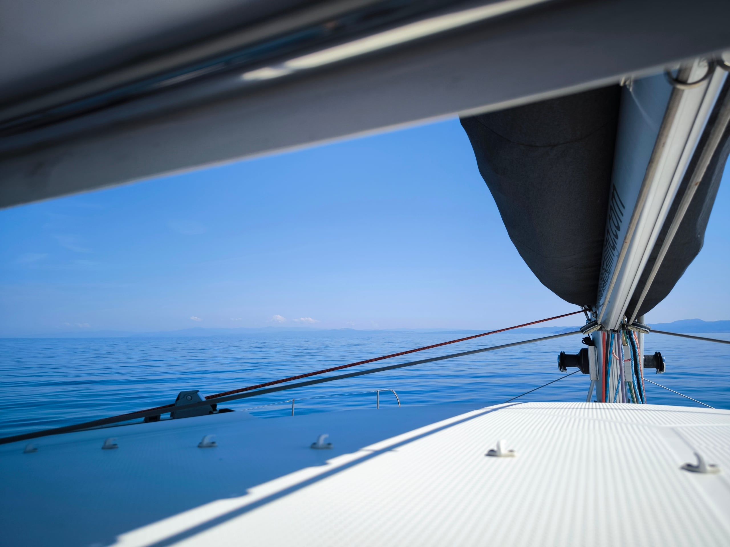 View from a catamaran’s deck across a calm, open sea