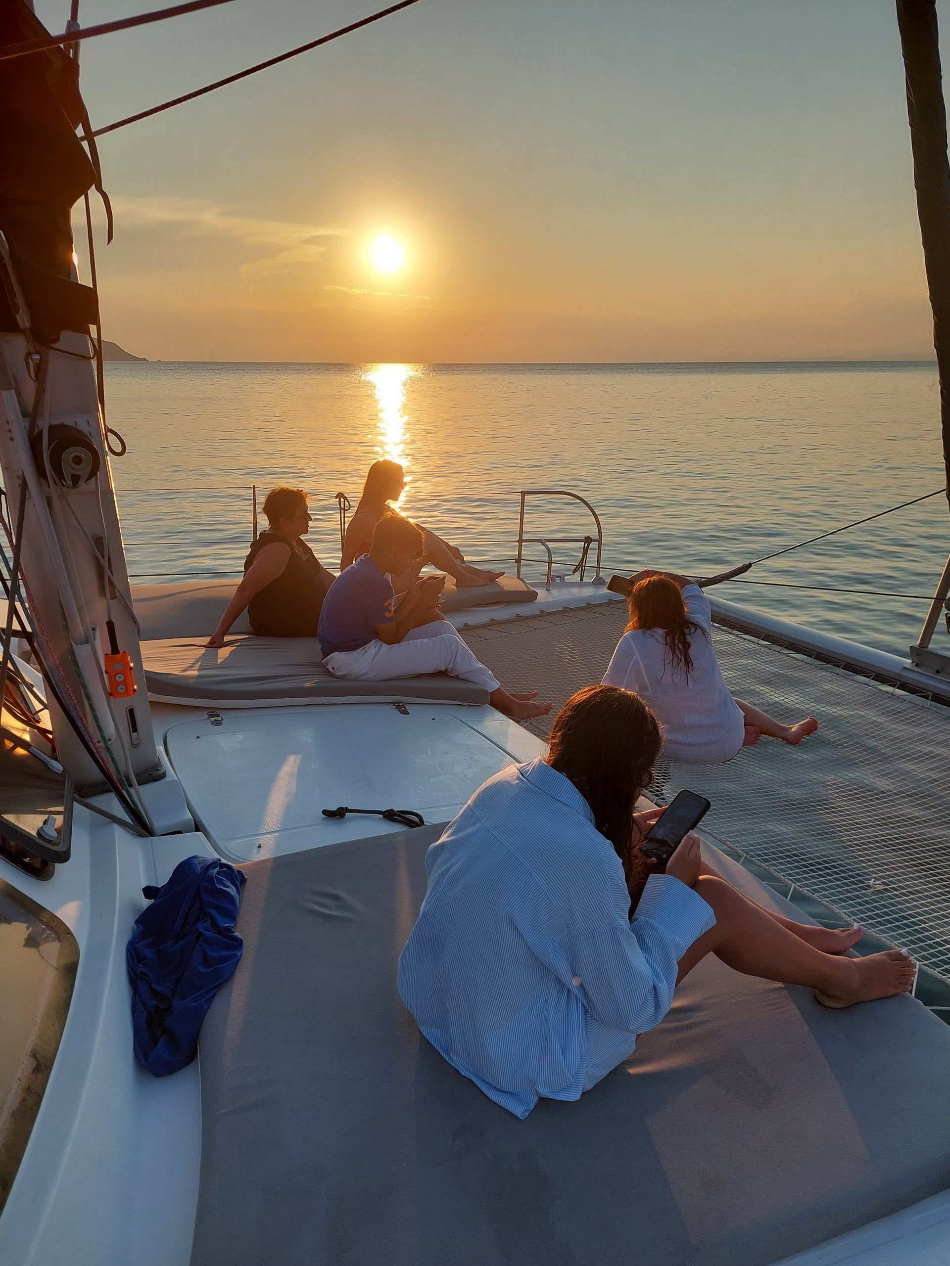 Guests watching from a catamaran’s bow on a sunset cruise from Porto Carras