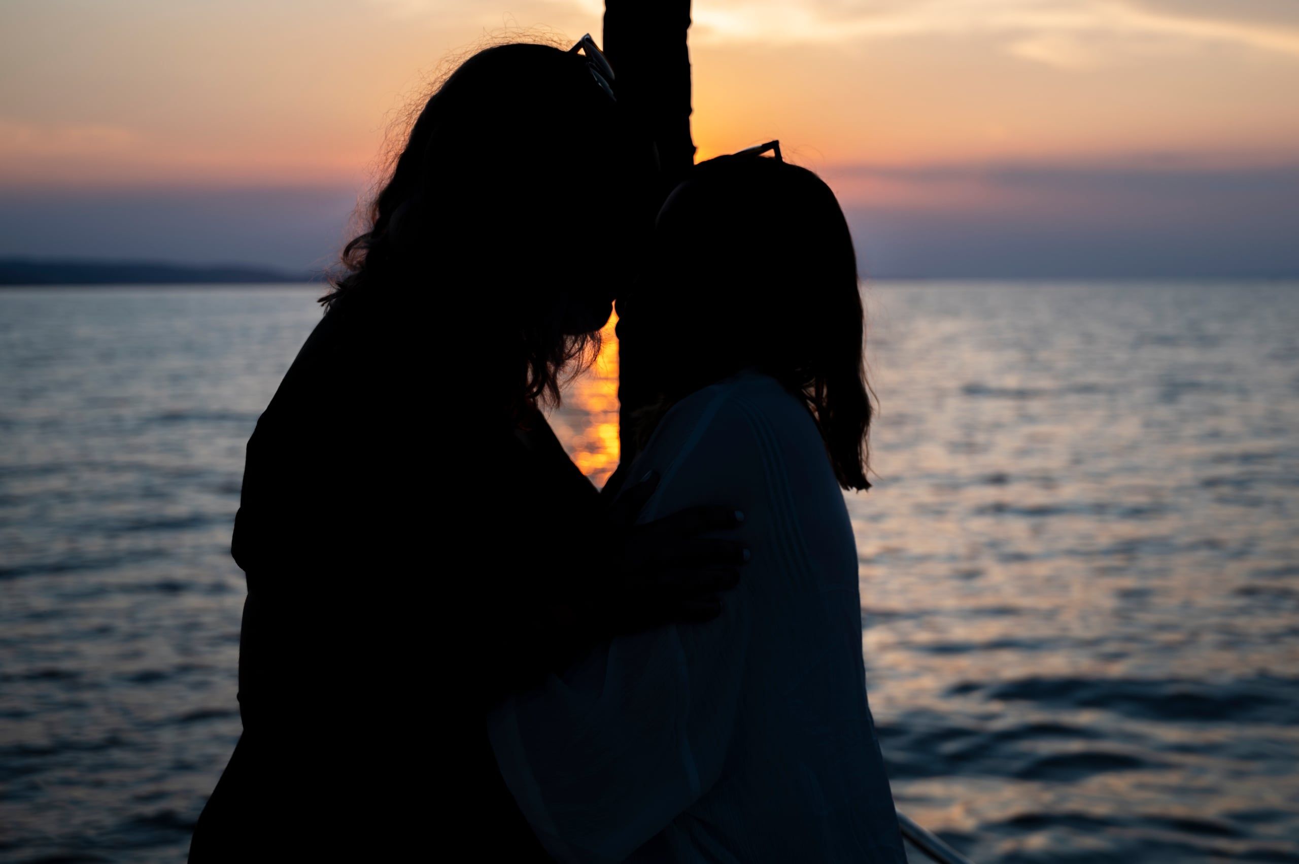 Silhouette of a couple embracing on a yacht as the sun sets over the sea
