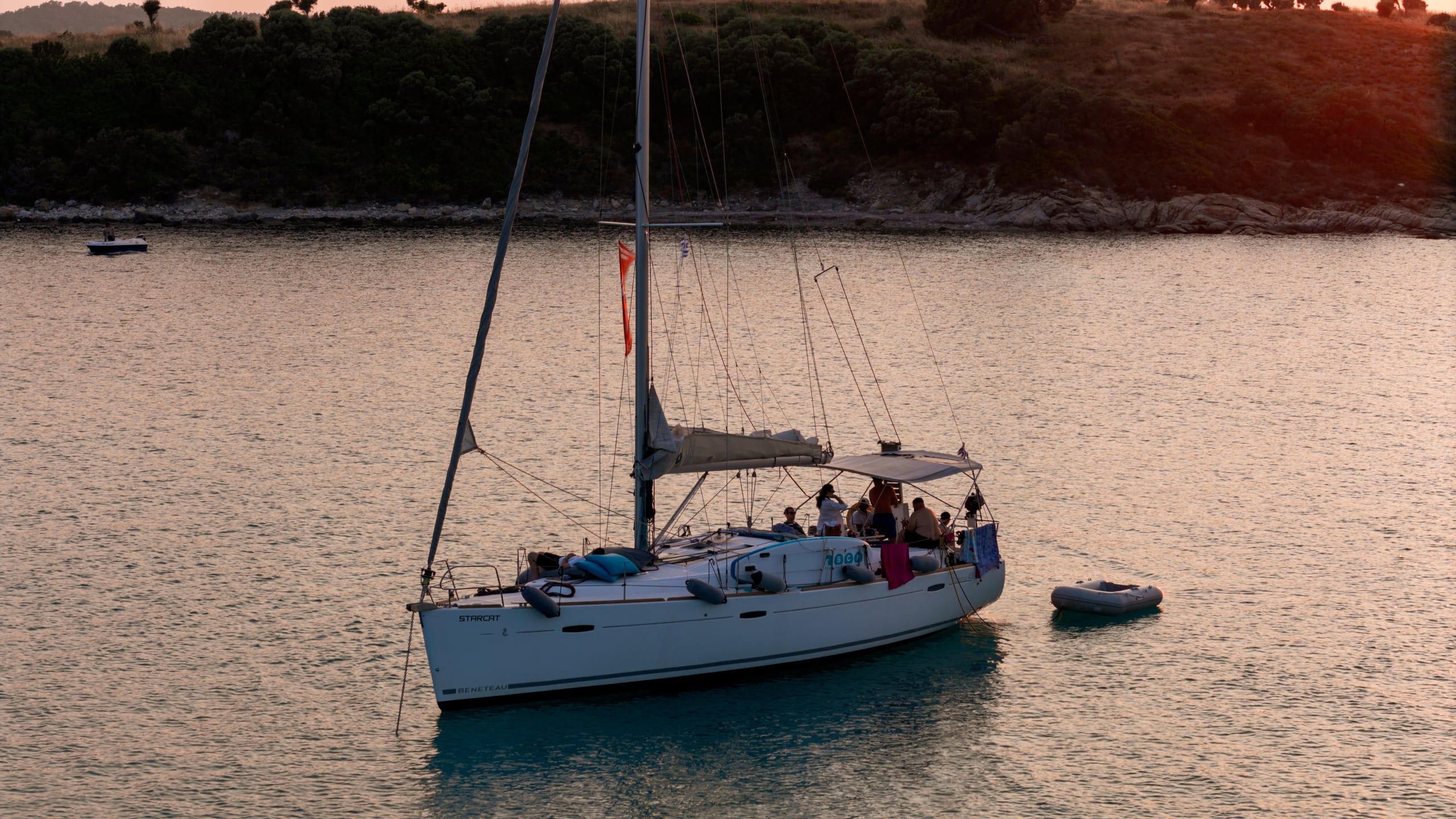 Guests on a sailing yacht at anchor off Diaporos in warm evening light