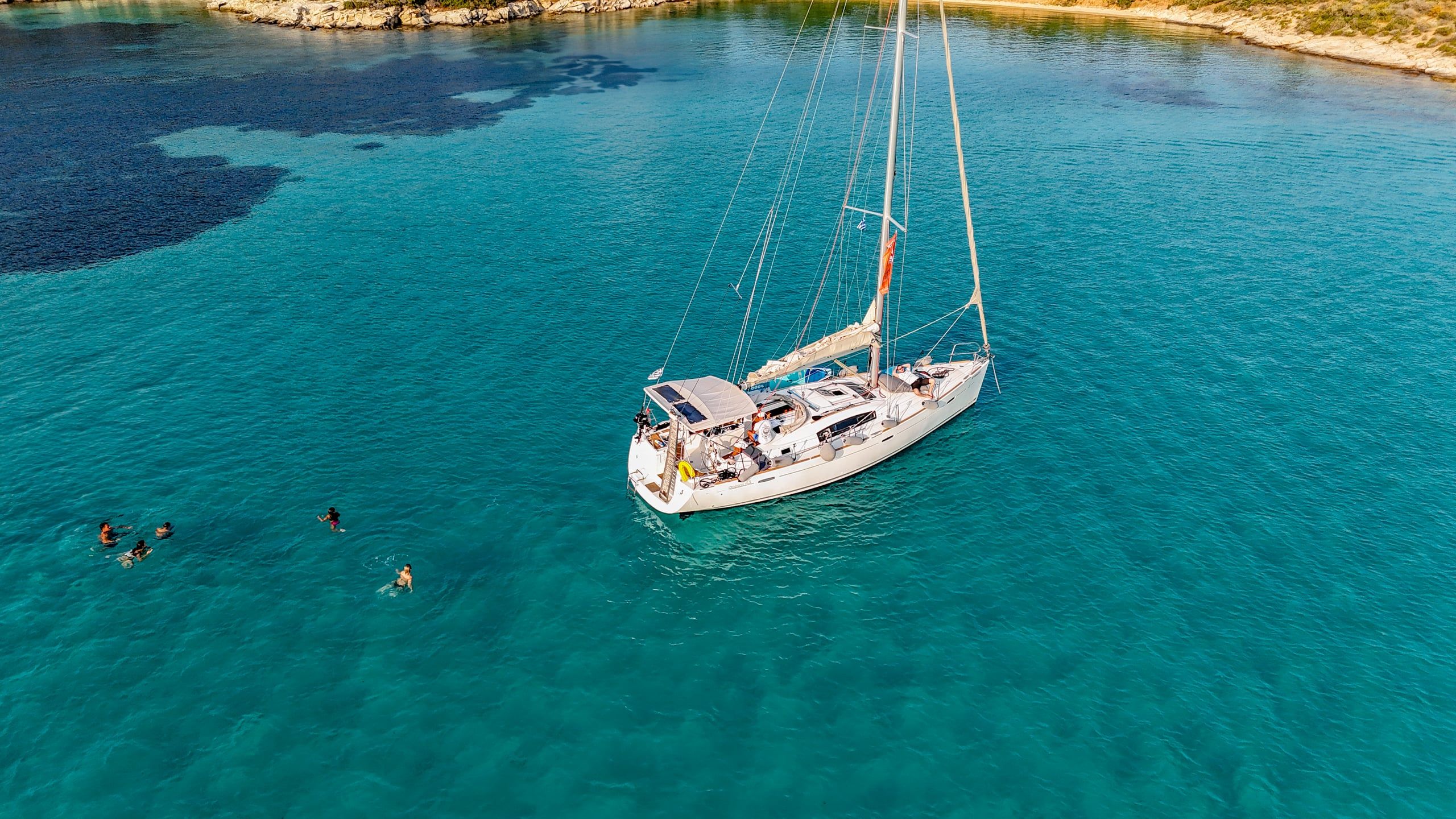 Guests swimming by a sailing yacht off Diaporos on a Blue Lagoon half-day cruise