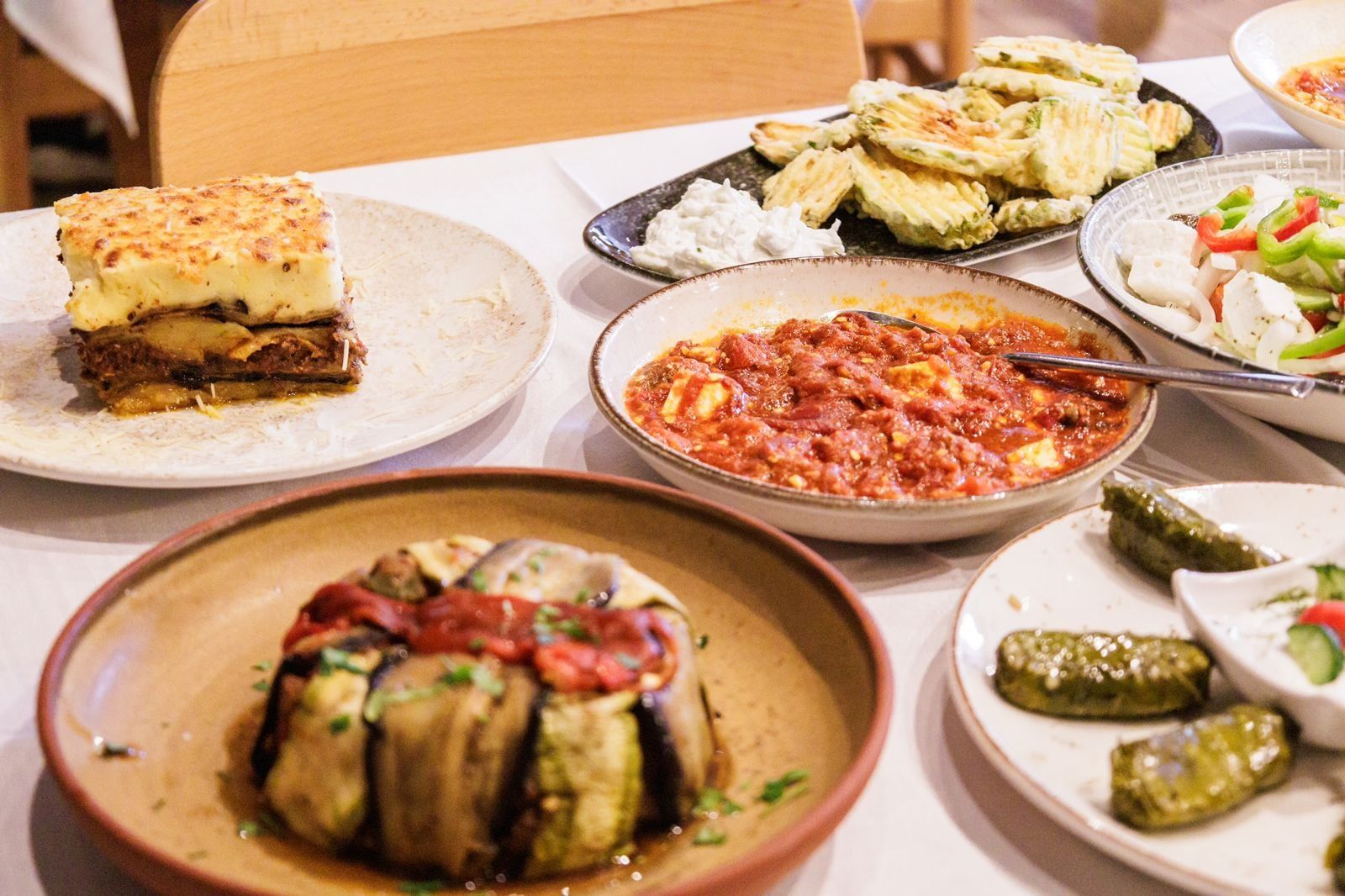 Lunch table with moussaka, stuffed vine leaves, dips and other Greek dishes