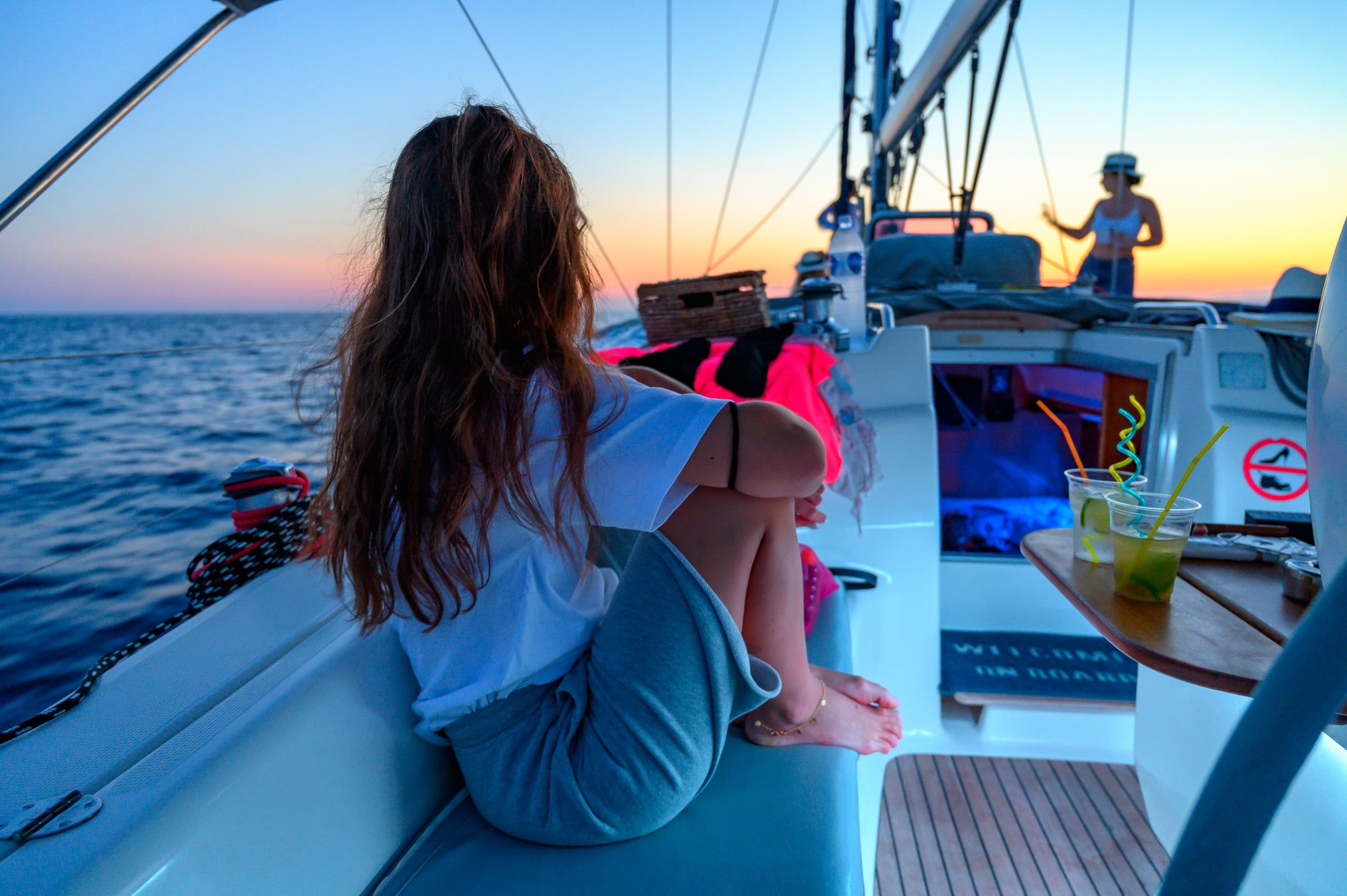 Orange sky over guests on a sailing yacht’s deck, a sunset cruise from Porto Carras