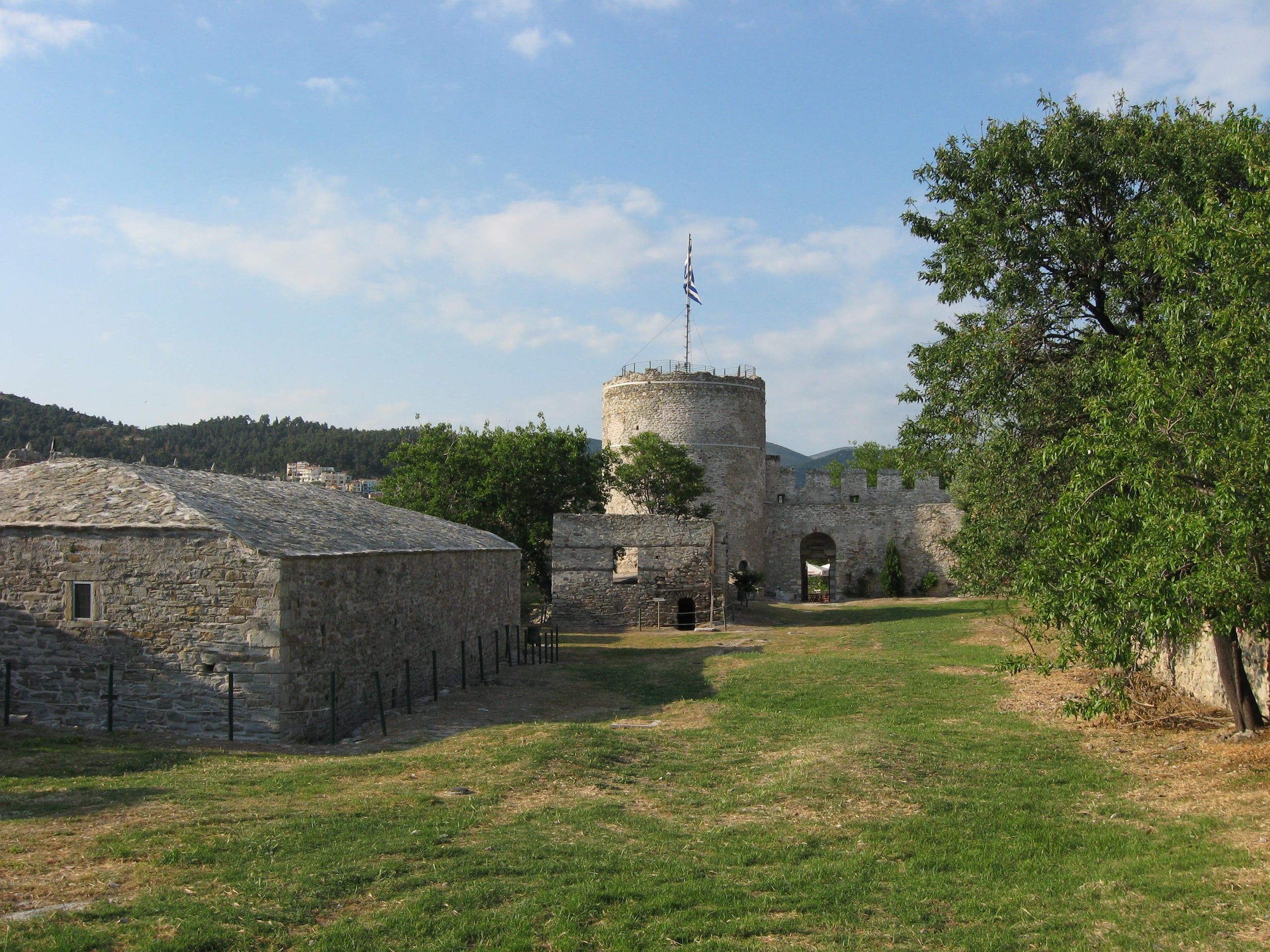 Stone buildings and a round tower inside the Kavala fortress on a sunny day