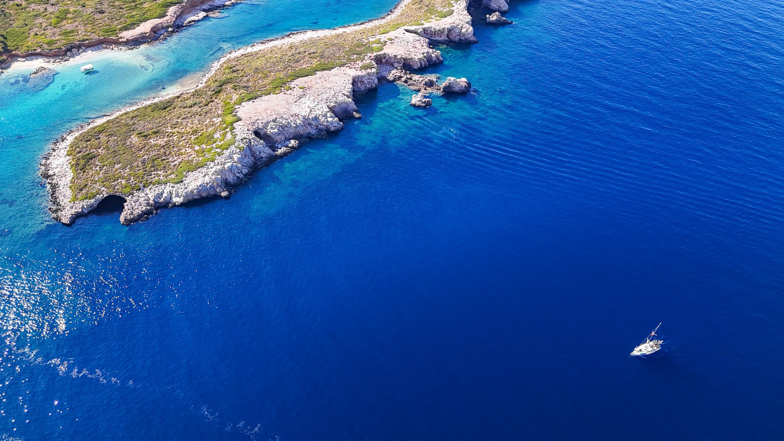 Sailing yacht island hopping in the Sporades, passing a long rocky island near Kyra Panagia