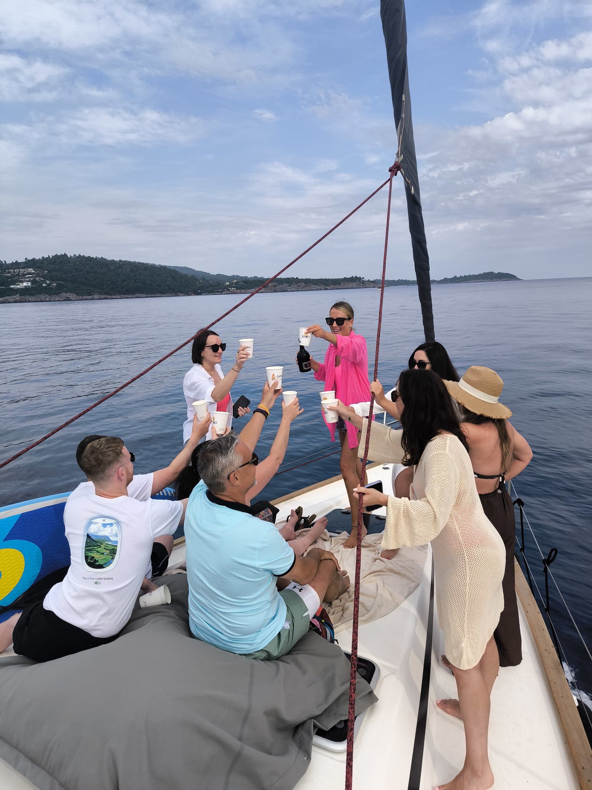 Friends toasting on the bow during a private sailing cruise off the coast of Kassandra