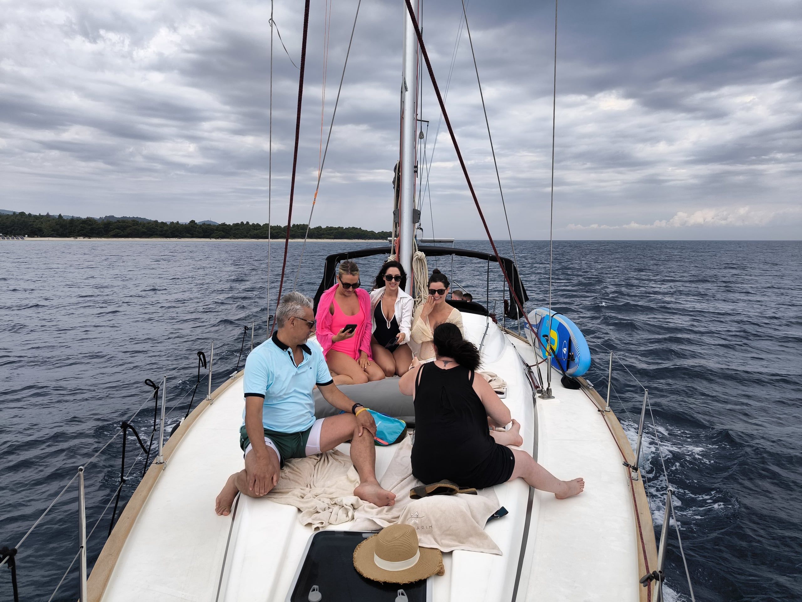 Guests chatting on a sailing yacht’s bow under a cloudy sky off Kassandra