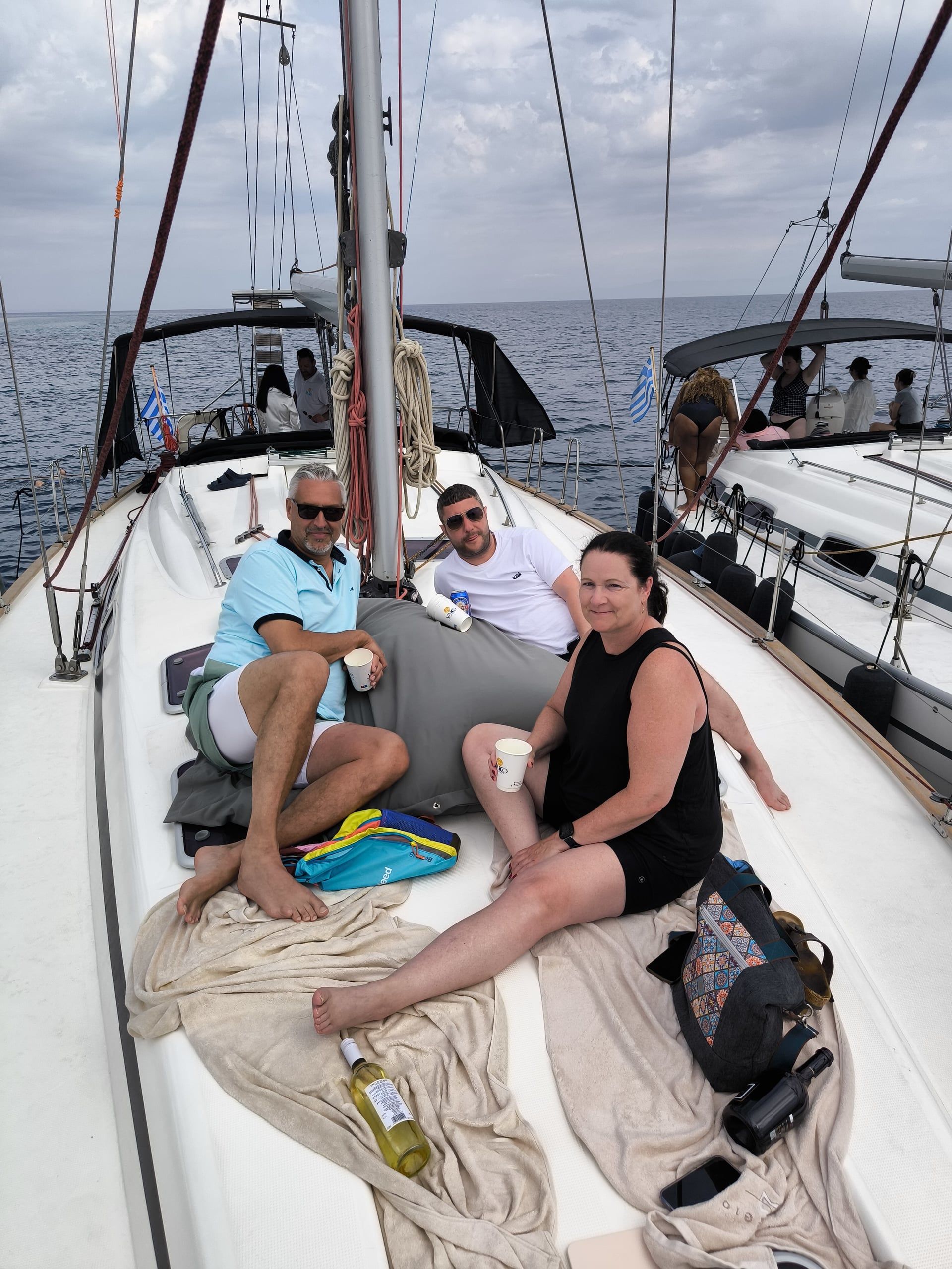 Guests relaxing on the bow beside another yacht on a half-day sailing trip off Kassandra