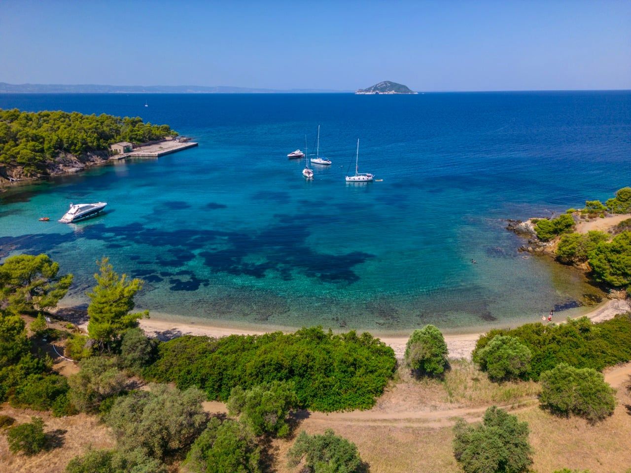 Sailing yachts anchored near Porto Carras on a day cruise, an islet on the horizon