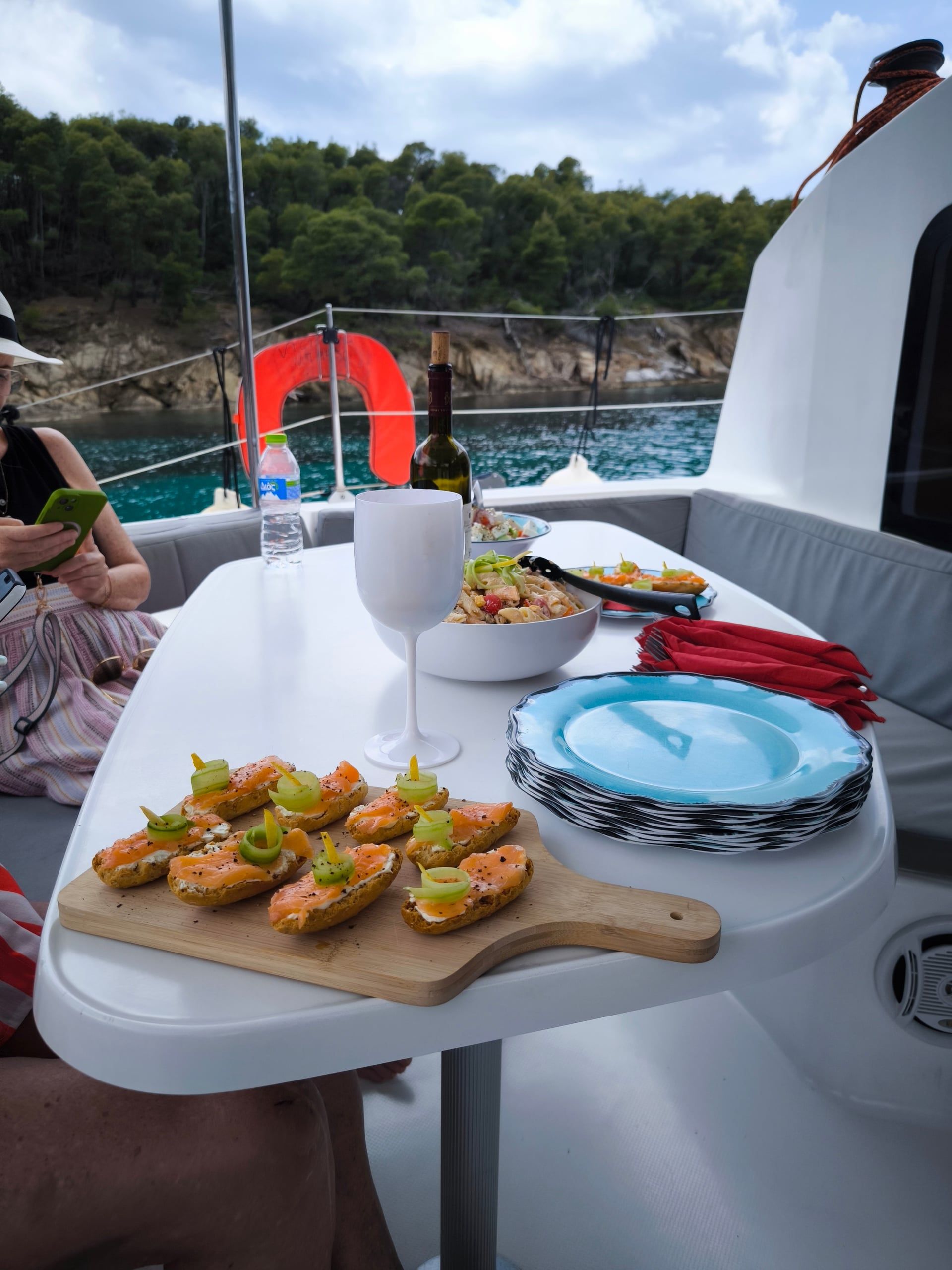 Platter of snacks and drinks on a catamaran table, a pine shore behind