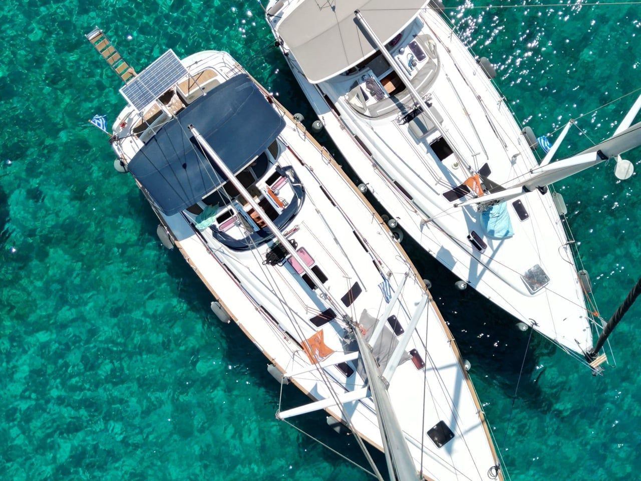 Two sailing yachts rafted together over clear green water near Porto Carras, seen from above