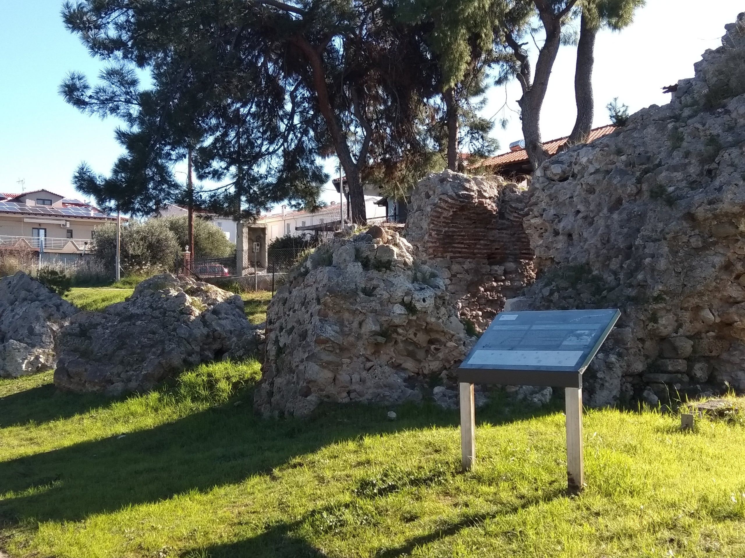 Remains of the ancient city walls of Potidea with an information sign