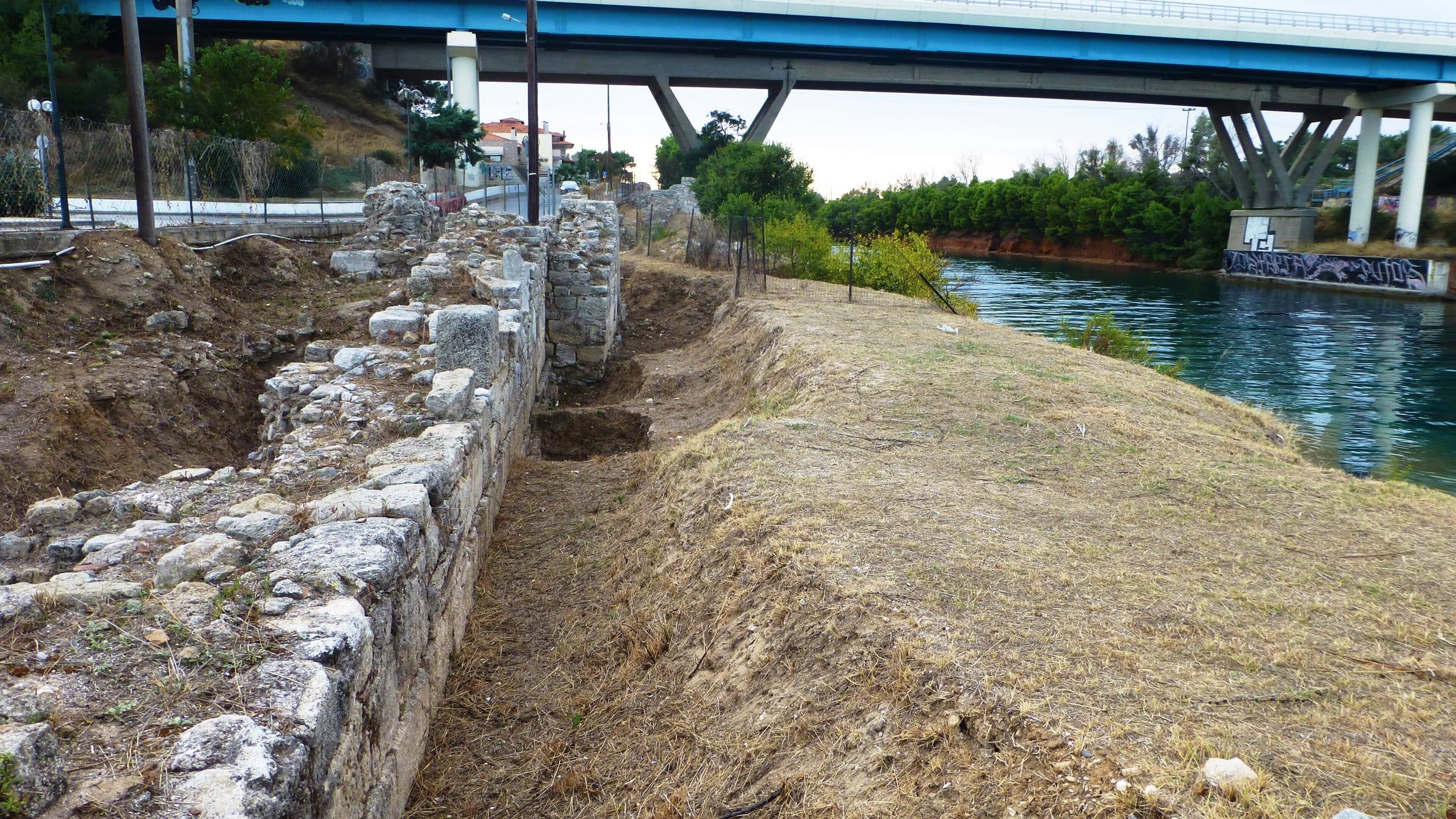 Ancient stone wall beside the Potidea canal under the modern road bridge