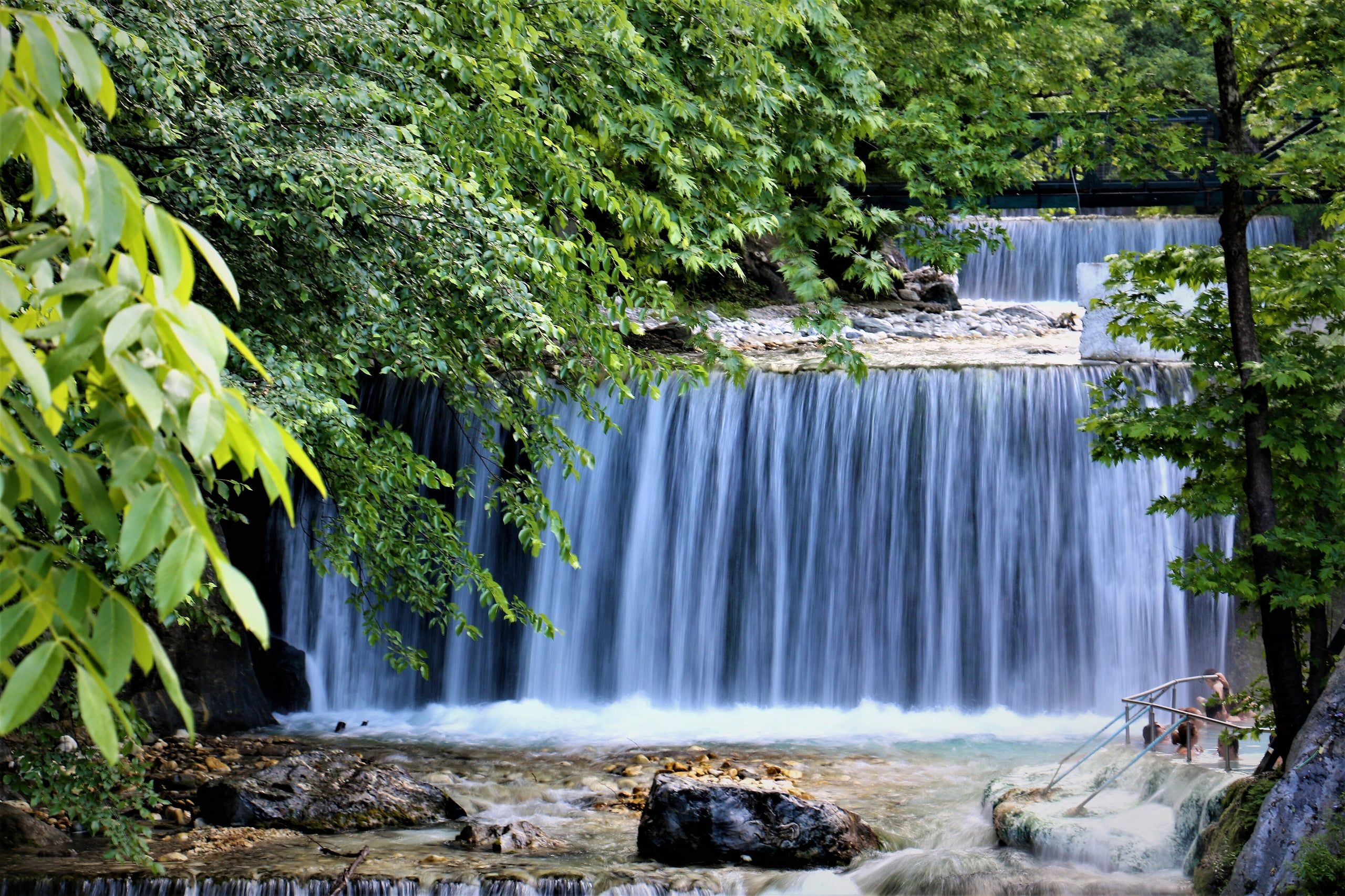 Stream and waterfall framed by leafy trees near the Pozar thermal baths