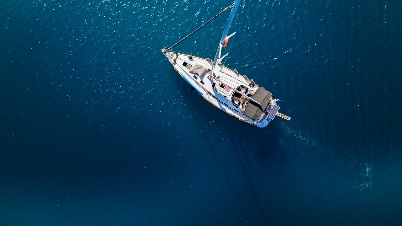 Sailing yacht crossing deep blue open sea, seen from directly above