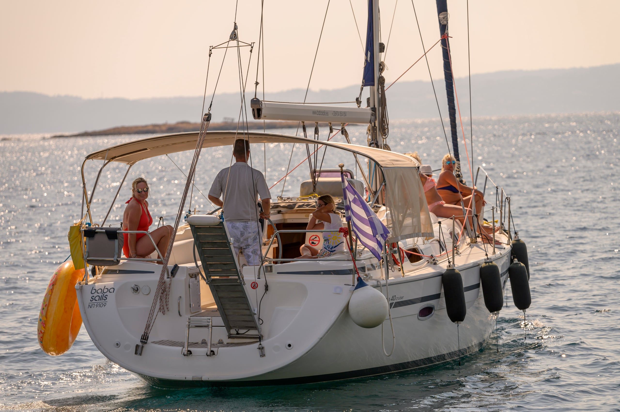 Guests relaxing on a sailing yacht at anchor in soft evening light