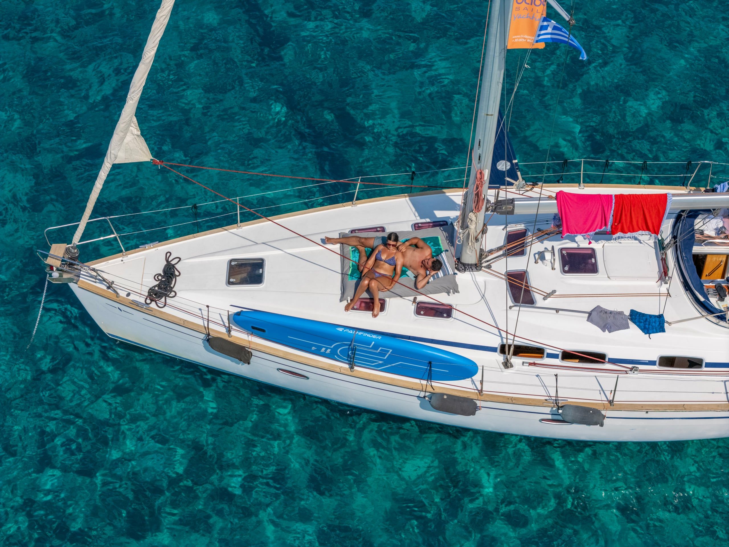 Couple sunbathing on the deck of a sailing yacht, seen from above