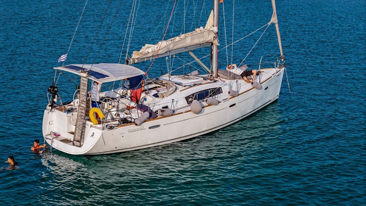 Guests swimming by a sailing yacht’s stern on a half-day trip from Porto Carras