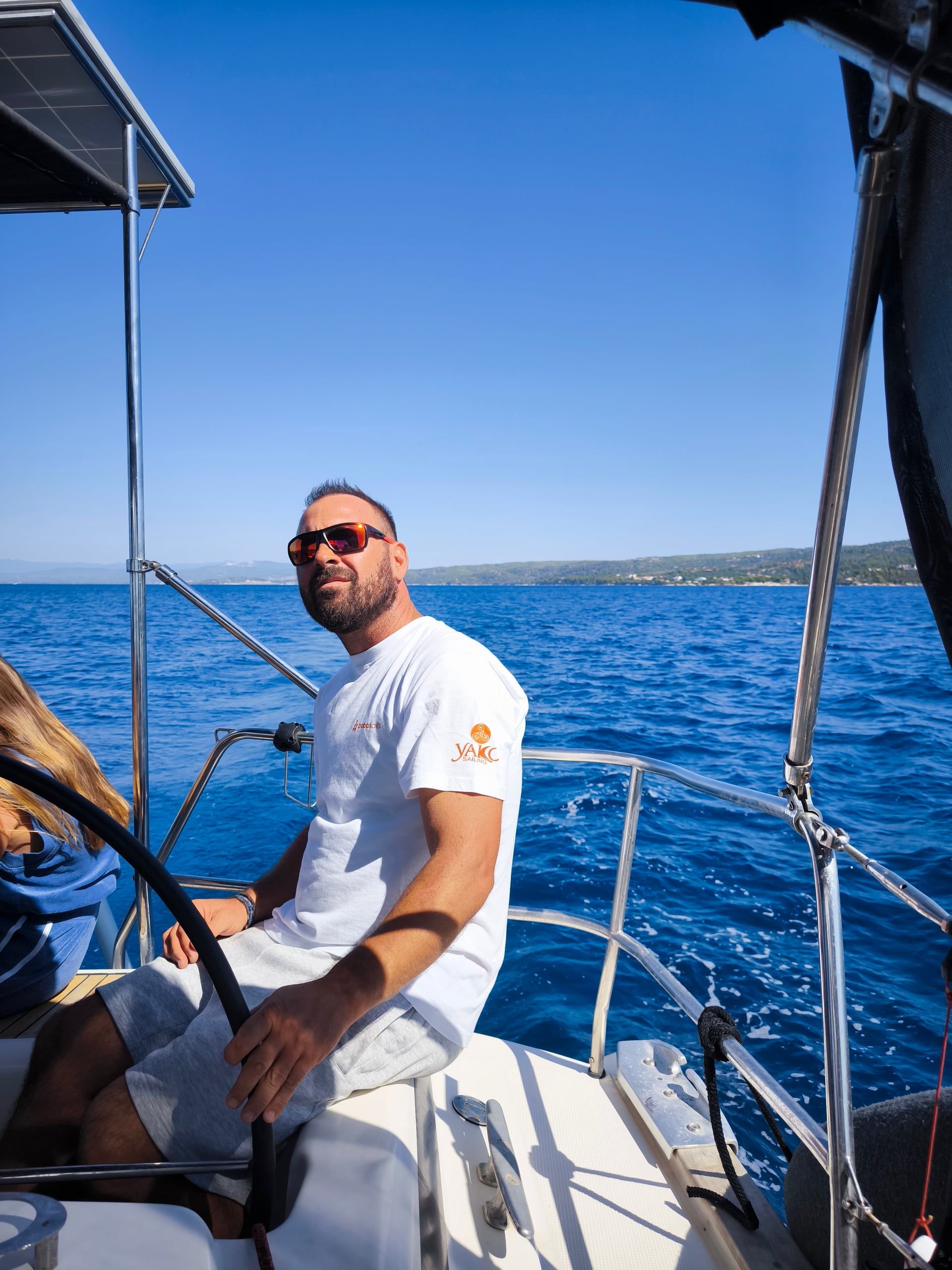 Man steering a sailing yacht across deep blue water
