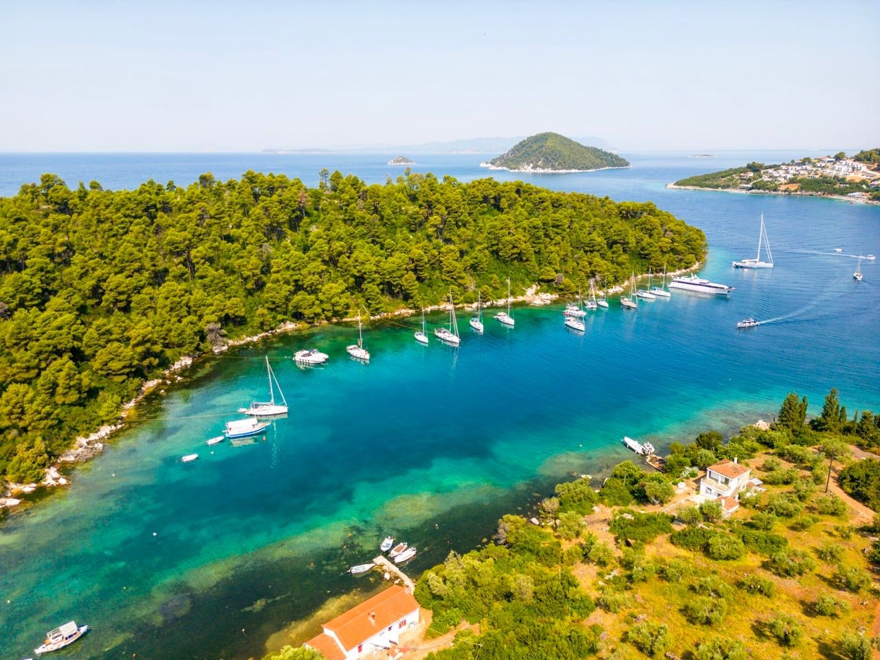 Sailing yachts anchored along the wooded shore of Panormos bay on Skopelos