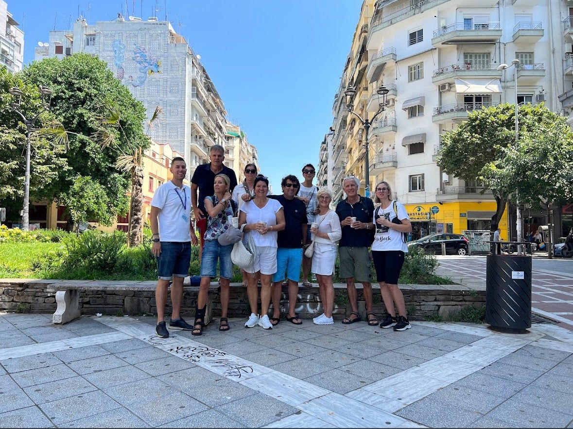 A tour group posing together on a tree lined street in Thessaloniki