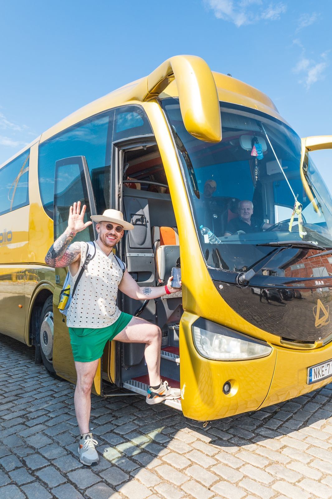 Smiling traveller stepping out of a yellow tour coach on a sunny day