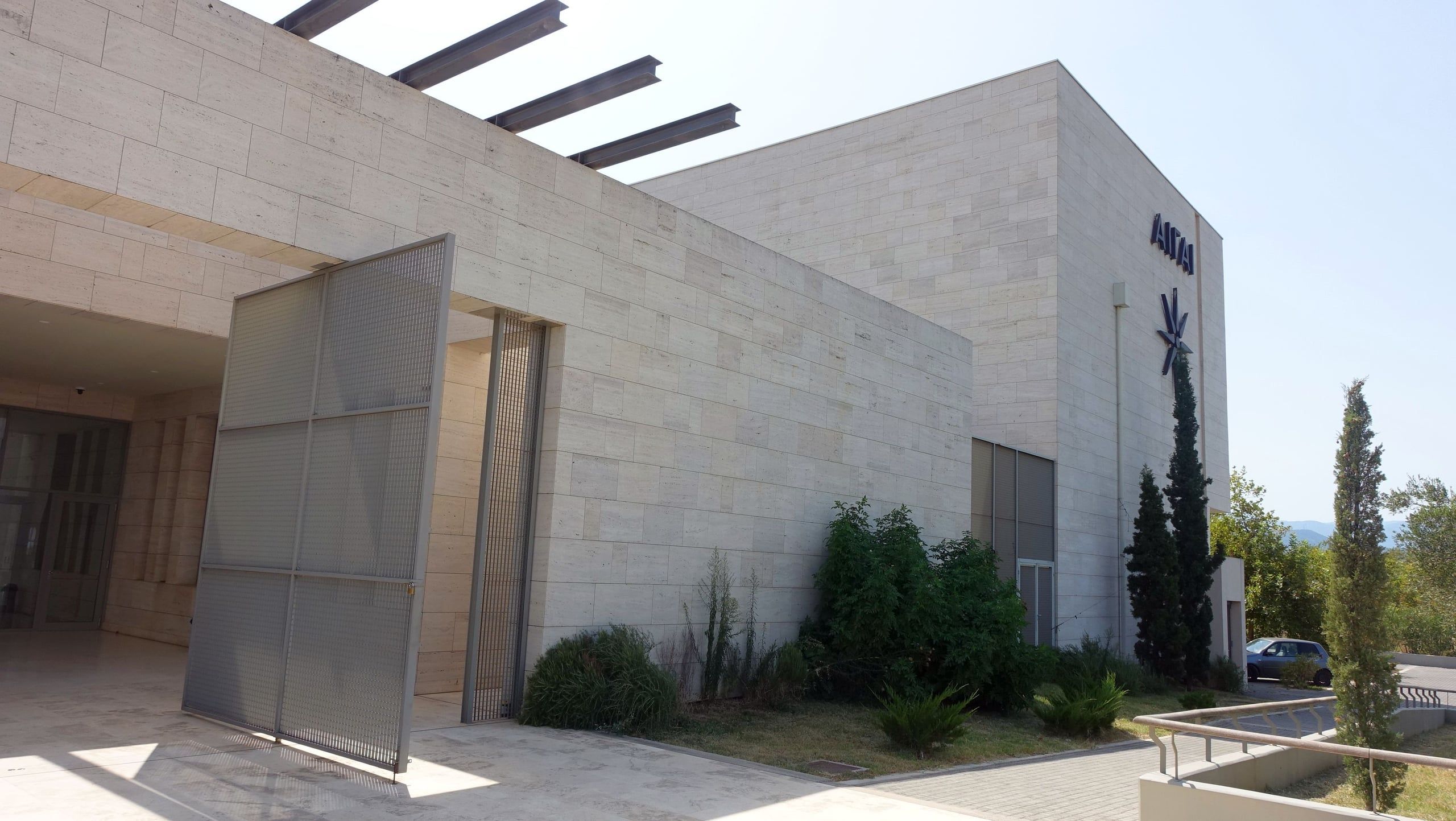 Modern stone museum building at Vergina with cypress trees and a sunny courtyard